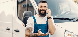 Οδηγός βαν στέκεται μπροστά από το όχημά του καθώς μιλά στο κινητό χαμογελώντας