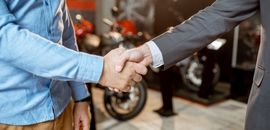 Πωλητής αντιπροσωπείας μηχανών σε χειραψία με πελάτη
