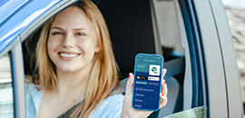 Χαμογελαστή οδηγός δείχνει την σελίδα του My Auto στο κινητό της