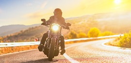 Οδηγός μηχανής εν κινήσει με φόντο το ηλιοβασίλεμα